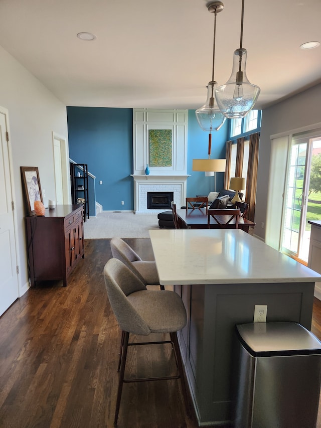 kitchen with a fireplace, dark wood finished floors, recessed lighting, hanging light fixtures, and light countertops