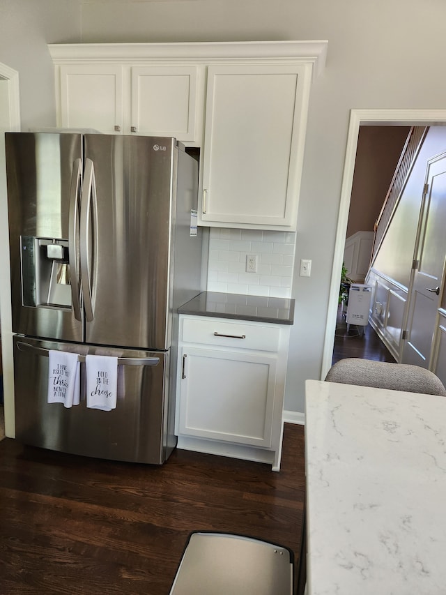 kitchen featuring stainless steel fridge with ice dispenser, dark wood-type flooring, tasteful backsplash, white cabinetry, and dark countertops