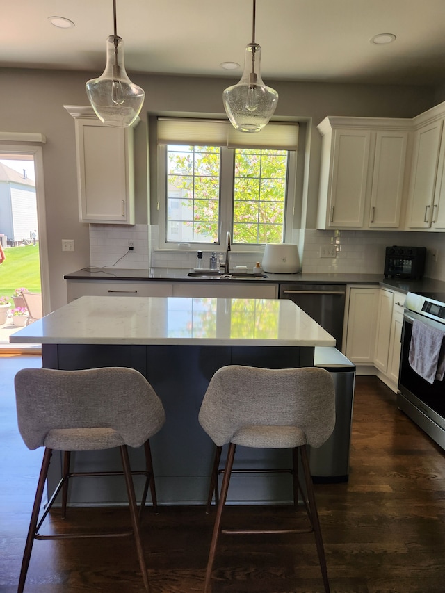 kitchen with a sink, stainless steel appliances, recessed lighting, white cabinetry, and backsplash