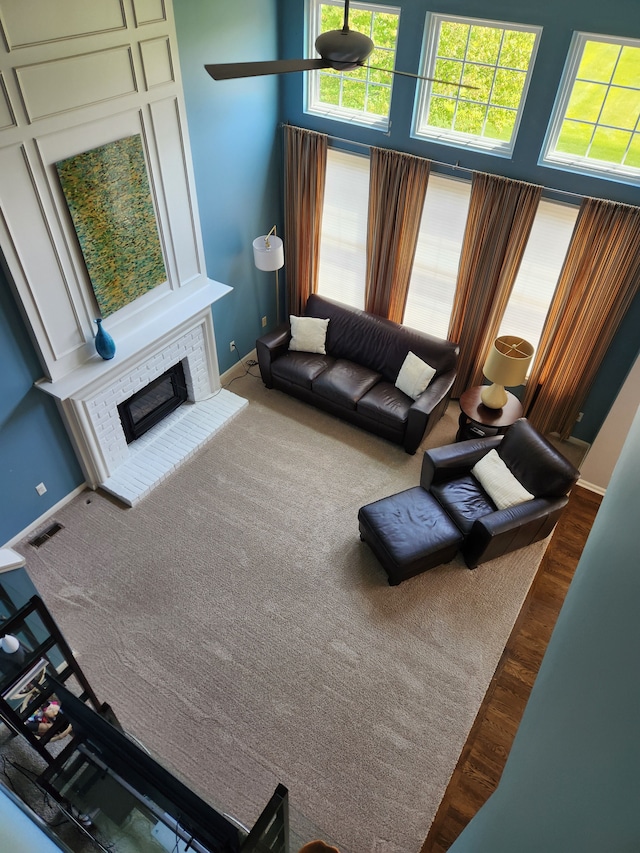 living room featuring a fireplace, plenty of natural light, wood finished floors, and baseboards
