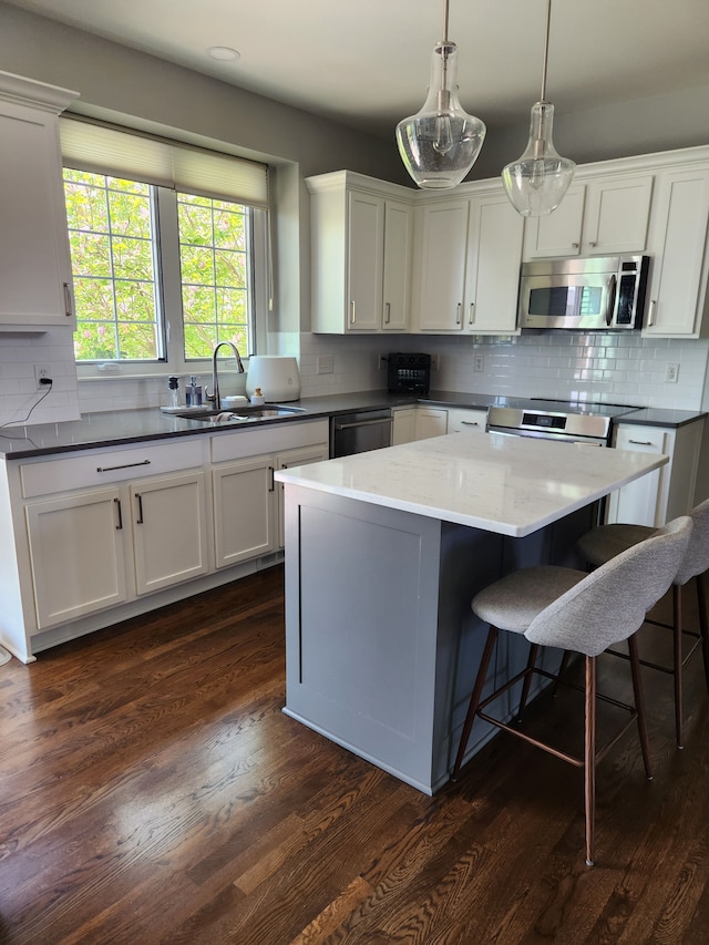 kitchen with stainless steel appliances, a sink, tasteful backsplash, and white cabinetry
