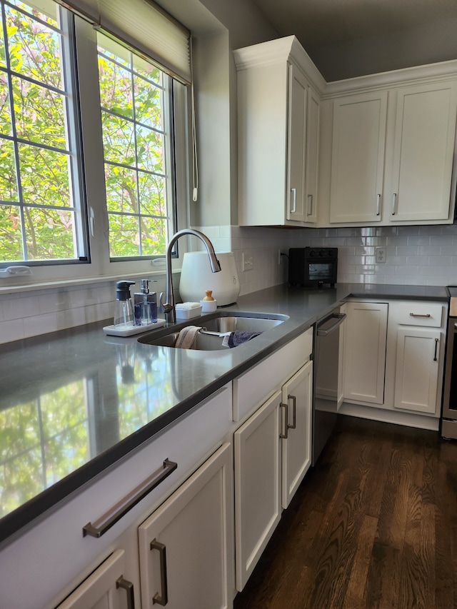 kitchen with a sink, dark wood-style flooring, stainless steel dishwasher, and white cabinetry