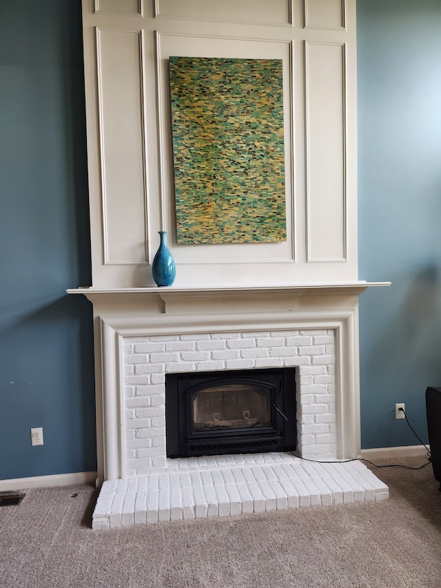 detailed view of carpet, baseboards, and a brick fireplace