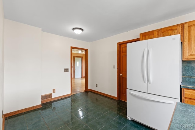11160 W Ridgeville Rd, Morenci, MI 49256 - kitchen with freestanding refrigerator, baseboards, brown cabinetry, and dark countertops