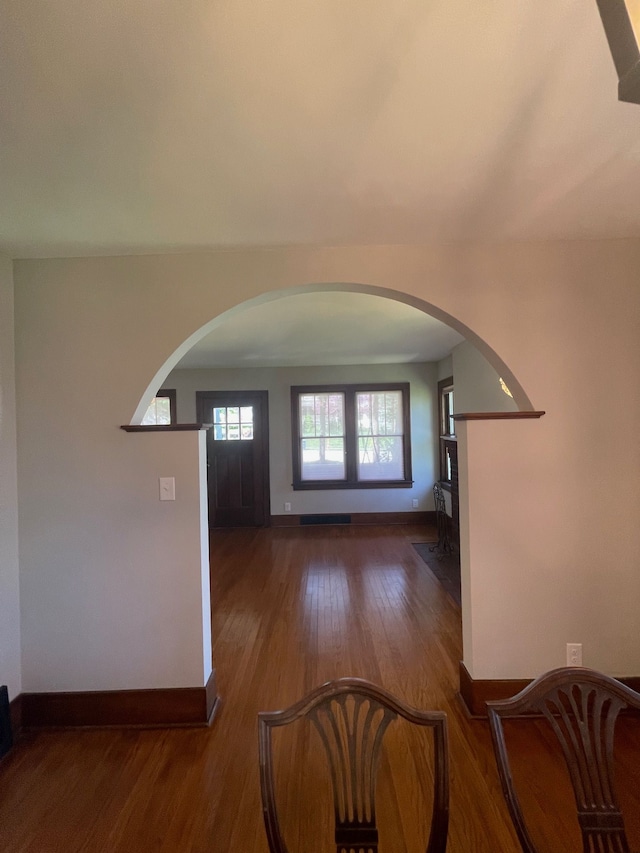 entrance foyer with wood finished floors, arched walkways, and baseboards