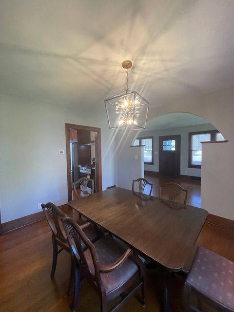dining area featuring a chandelier, wood finished floors, arched walkways, and baseboards