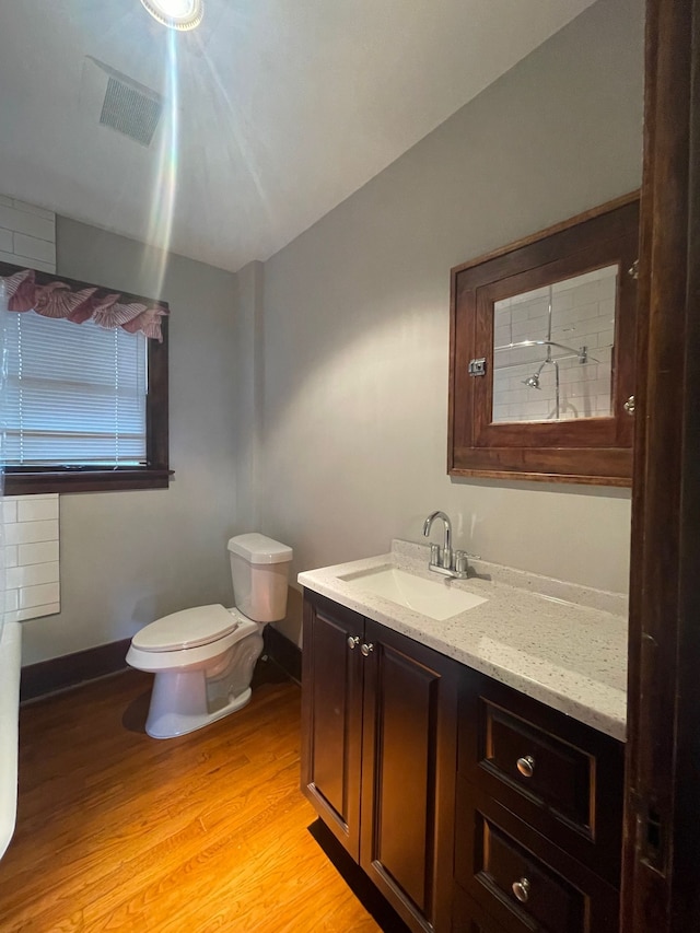 bathroom with vanity, toilet, wood finished floors, and baseboards