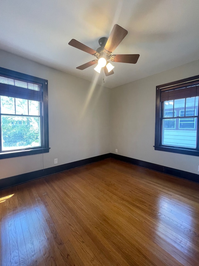 empty room with dark wood-style flooring, ceiling fan, and baseboards