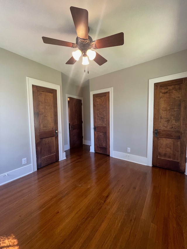 unfurnished bedroom with dark wood-style flooring, baseboards, and a ceiling fan