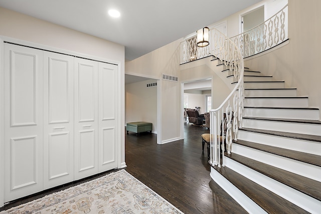 foyer featuring a chandelier, dark wood-type flooring, stairway, and baseboards