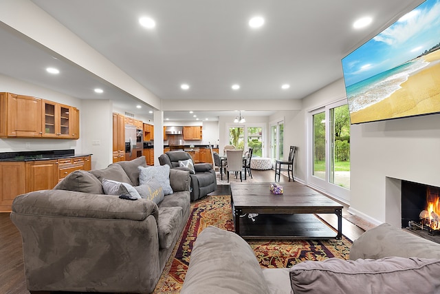 living room featuring wood finished floors, recessed lighting, a warm lit fireplace, and baseboards