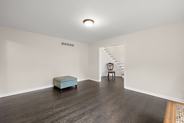 empty room with dark wood-type flooring, stairs, and baseboards