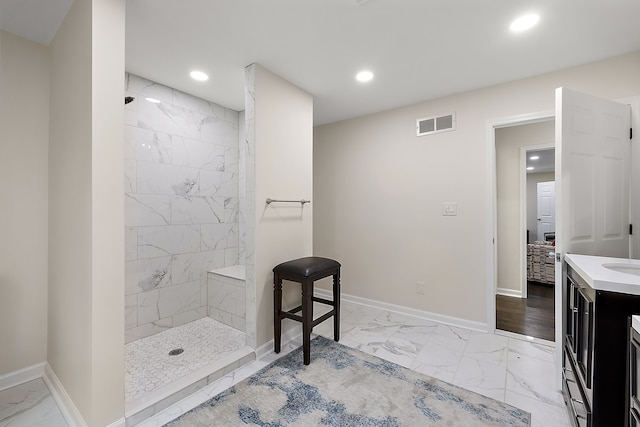 bathroom with marble look tiles, a tile shower, baseboards, recessed lighting, and vanity
