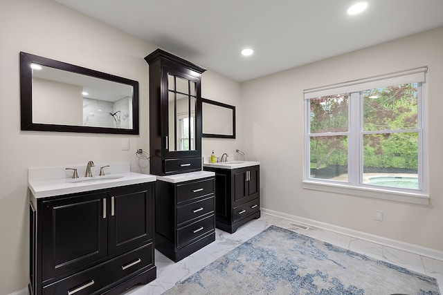 bathroom with marble finish floors, baseboards, a shower, two vanities, and recessed lighting
