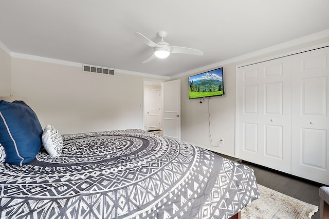 bedroom with dark wood-style floors, a closet, a ceiling fan, and crown molding