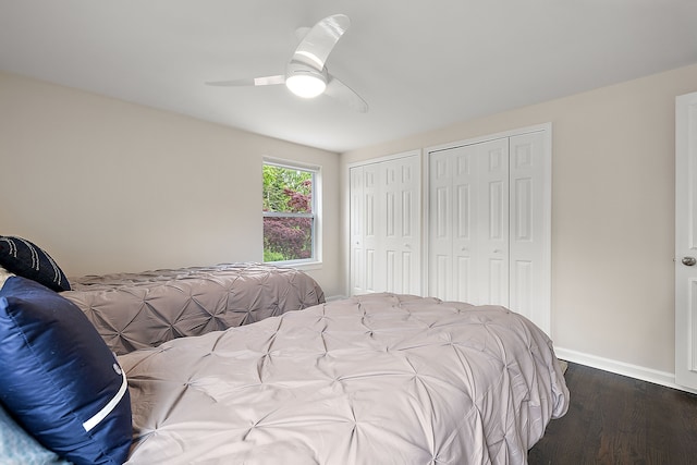 bedroom with two closets, dark wood finished floors, baseboards, and a ceiling fan