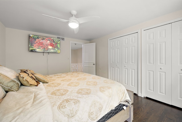 bedroom featuring multiple closets, dark wood-style floors, and a ceiling fan