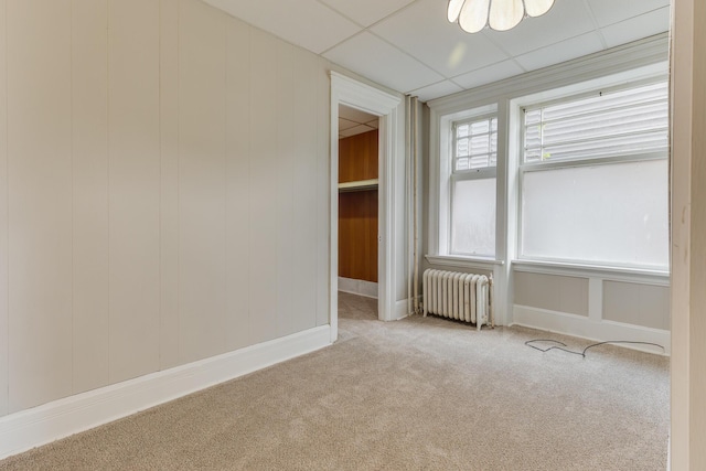 spare room with radiator, carpet flooring, and a paneled ceiling