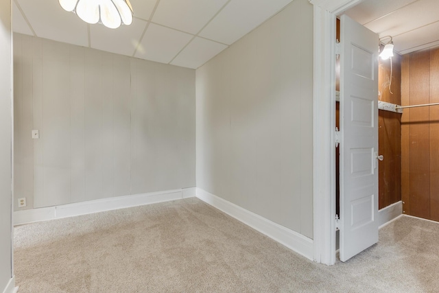spare room featuring carpet flooring, a drop ceiling, and baseboards
