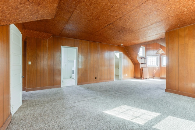 additional living space with carpet flooring and wooden walls