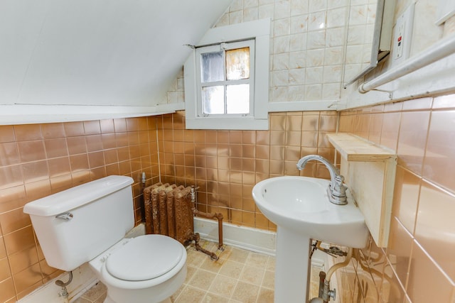 bathroom with tile walls, lofted ceiling, radiator, and toilet