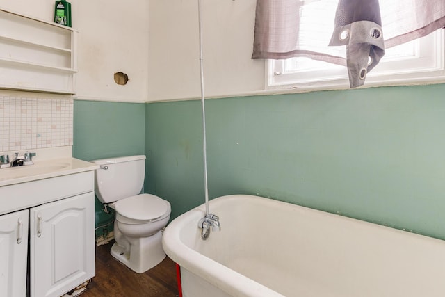 bathroom featuring a soaking tub, toilet, vanity, wood finished floors, and wainscoting
