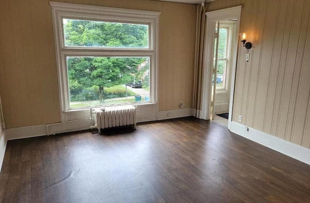 unfurnished room with radiator, dark wood-type flooring, and baseboards