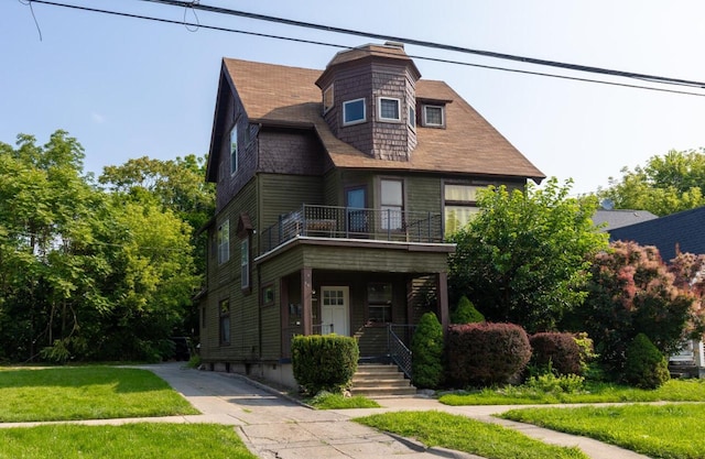 victorian home featuring a balcony, a front lawn, and a shingled roof