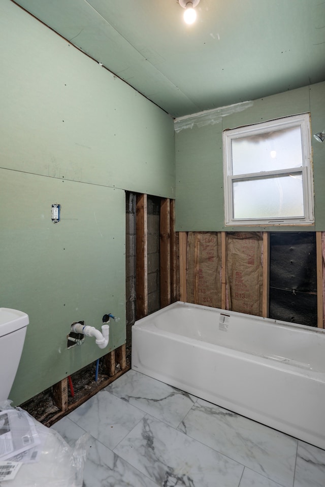 bathroom featuring a tub to relax in, marble finish flooring, and toilet