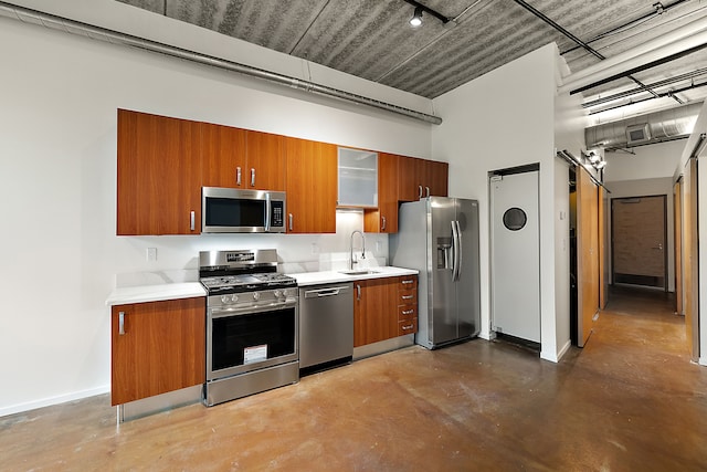 kitchen featuring stainless steel appliances, a sink, brown cabinetry, finished concrete floors, and light countertops