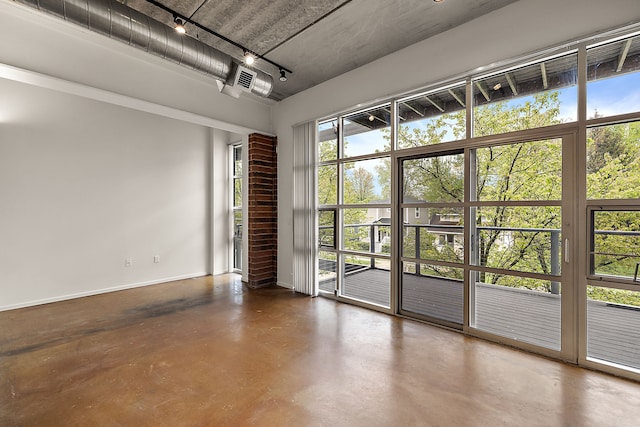 unfurnished room with concrete floors, rail lighting, and baseboards
