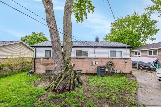 rear view of house featuring brick siding, a chimney, and central air condition unit