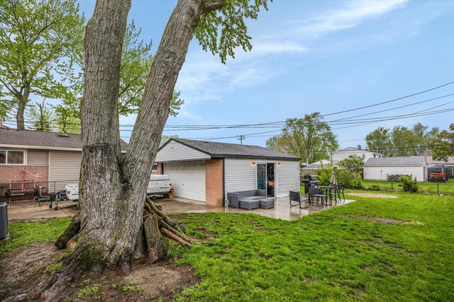 rear view of property featuring brick siding, a garage, an outbuilding, and a patio