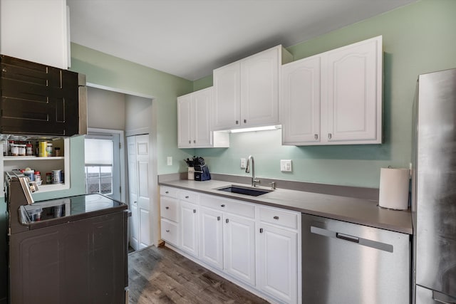 kitchen featuring stainless steel appliances, washer / clothes dryer, a sink, and white cabinetry