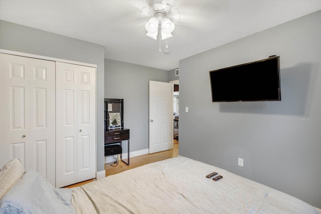 bedroom with a closet, wood finished floors, a ceiling fan, and baseboards