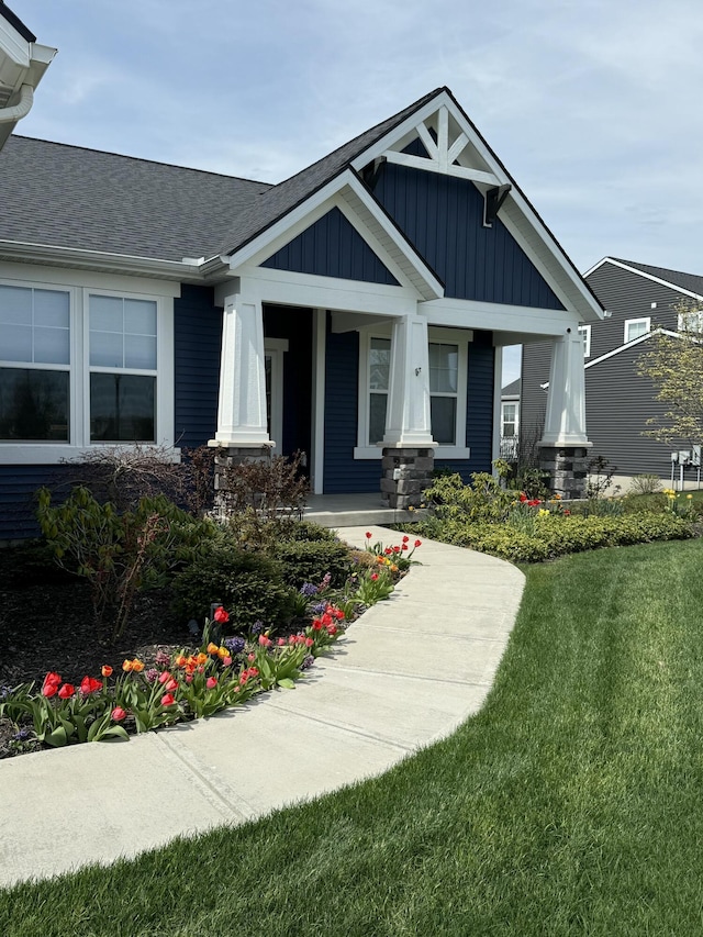 4497 Point Superior Ct, Holland, MI 49424 - craftsman house featuring board and batten siding, a front yard, a porch, and a shingled roof