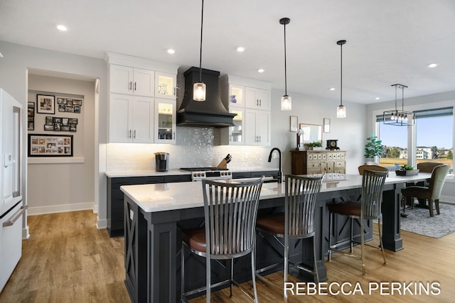 4497 Point Superior Ct, Holland, MI 49424 - kitchen featuring premium range hood, white cabinetry, backsplash, a center island with sink, and gas stove