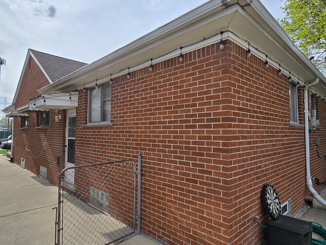 view of side of home featuring fence, a gate, and brick siding
