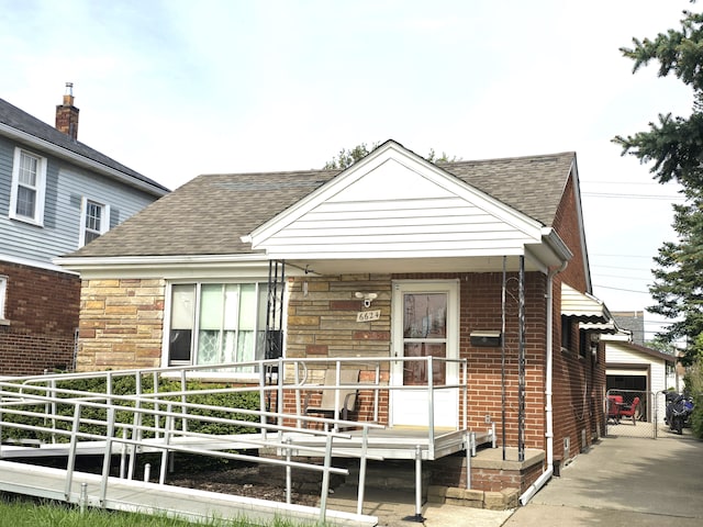view of front of property featuring a shingled roof, covered porch, and stone siding
