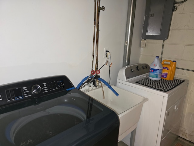 washroom featuring electric panel, separate washer and dryer, and concrete block wall