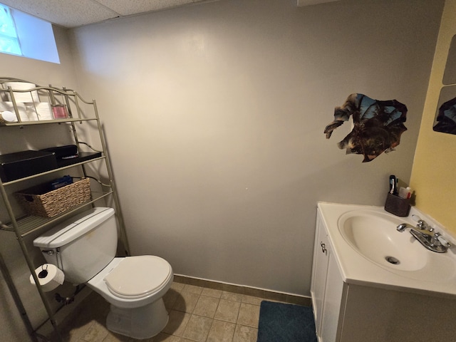 half bathroom with toilet, vanity, tile patterned flooring, and baseboards