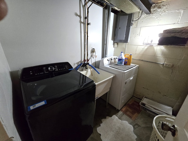 washroom with electric panel, concrete block wall, and independent washer and dryer