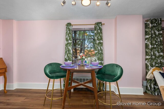 dining room featuring baseboards, wood finished floors, and a textured ceiling