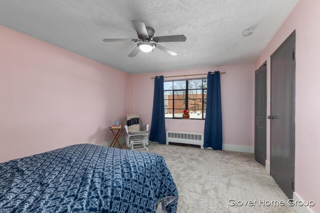 carpeted bedroom featuring radiator heating unit, a textured ceiling, a ceiling fan, and baseboards