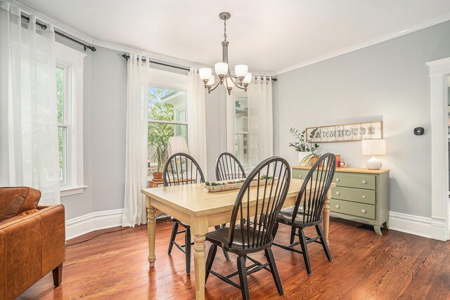 dining area featuring a chandelier, crown molding, dark wood-style floors, and baseboards
