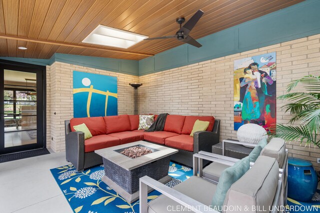 living area with brick wall, wood ceiling, and a ceiling fan
