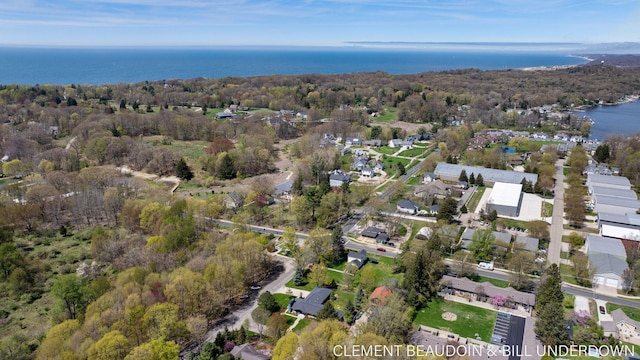 view of property location with a large body of water, nearby suburban area, and a forest