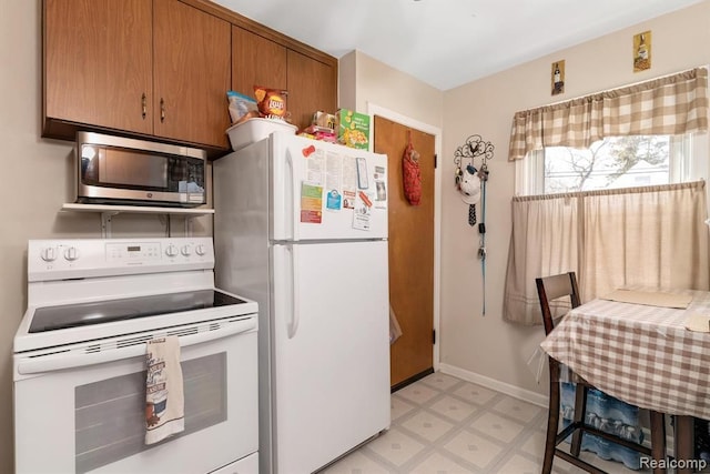 kitchen with white appliances, light floors, brown cabinets, and baseboards