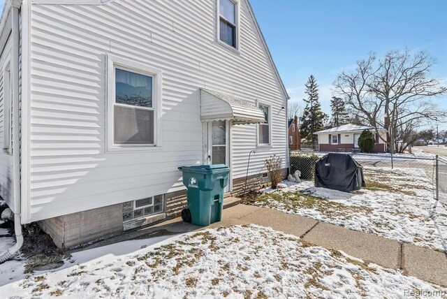snow covered rear of property featuring fence