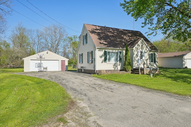cape cod-style house featuring an outbuilding, a detached garage, a front lawn, and roof with shingles
